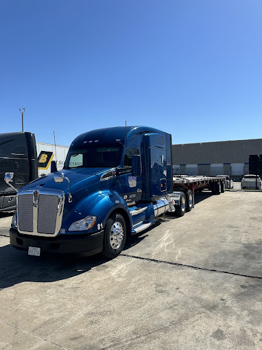 Blue Kenworth tractor with a flatbed trailer parked at the Bilbo yard