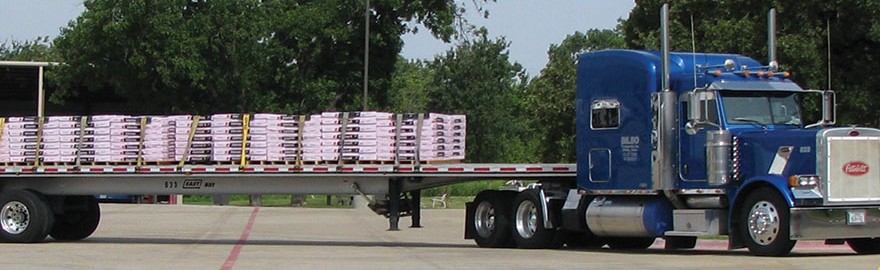 Blue Bilbo Transports Peterbilt tractor with a strapped flatbed load of palletized building materials